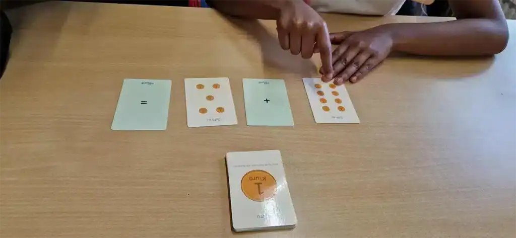 Två personer spelar ett matematiskt spel med kort på ett bord.